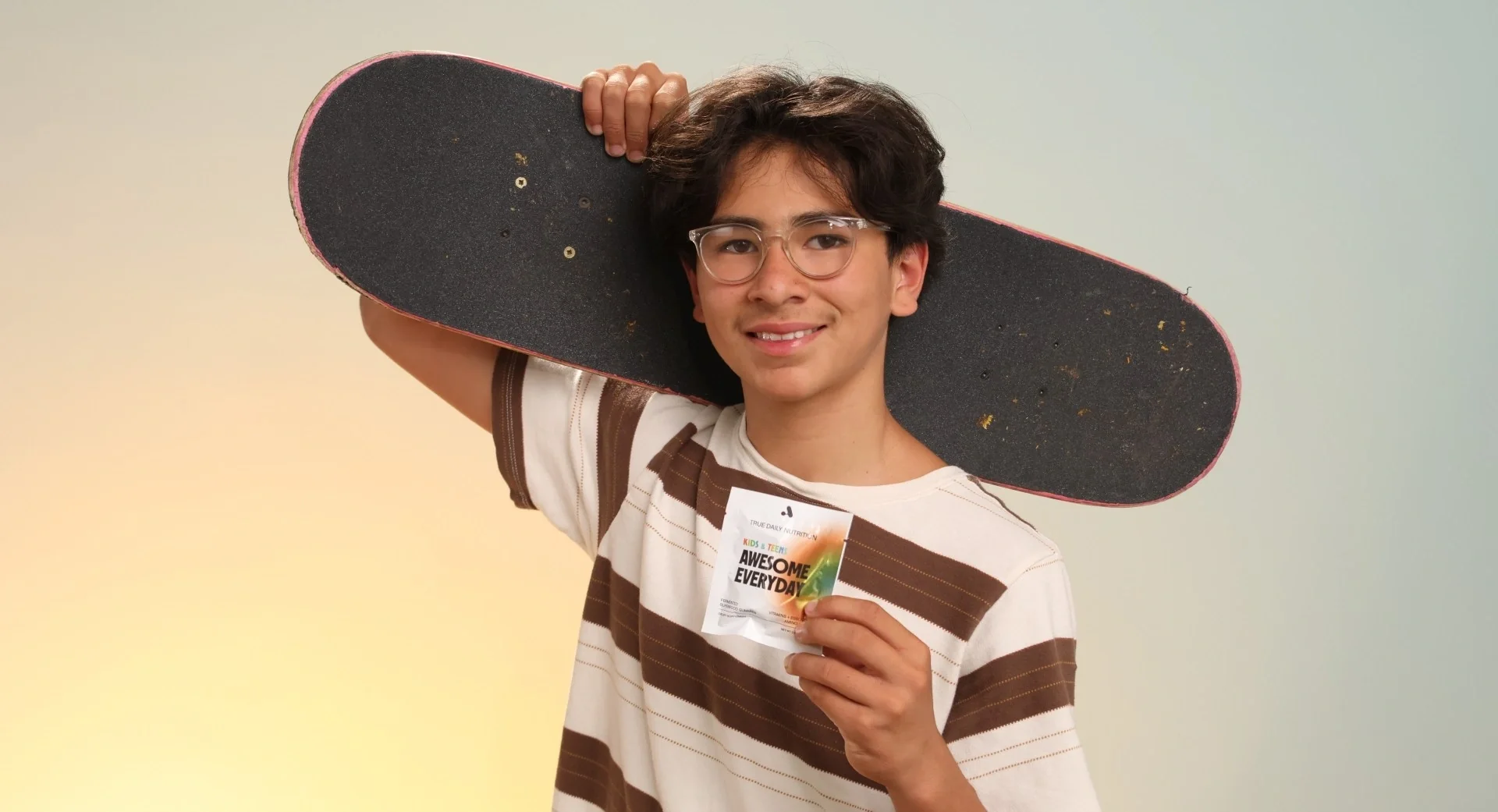 Boy holding an Awesome Everyday Kids & Teens packet with a skateboard for active daily nutrition.
